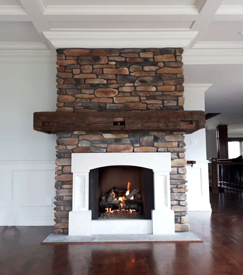 Custom stone fireplace with reclaimed timber mantel by Revel Homes