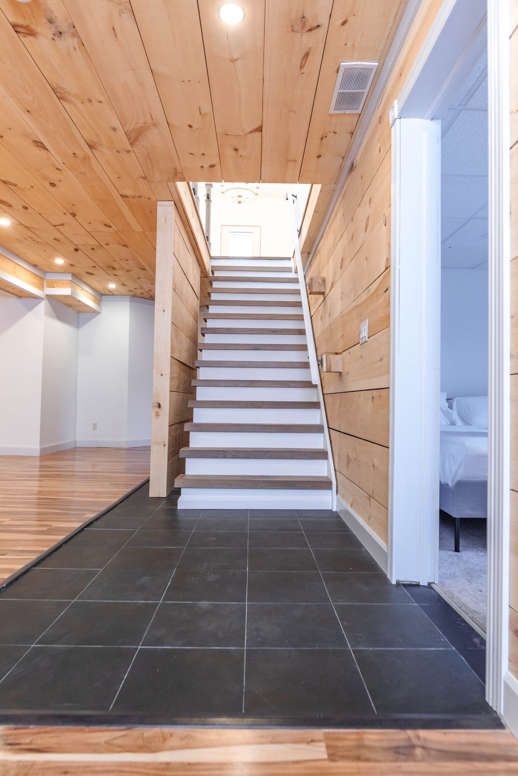 Basement renovation with pine feature walls and slate tile entry in a Wasaga Beach home by Revel Homes