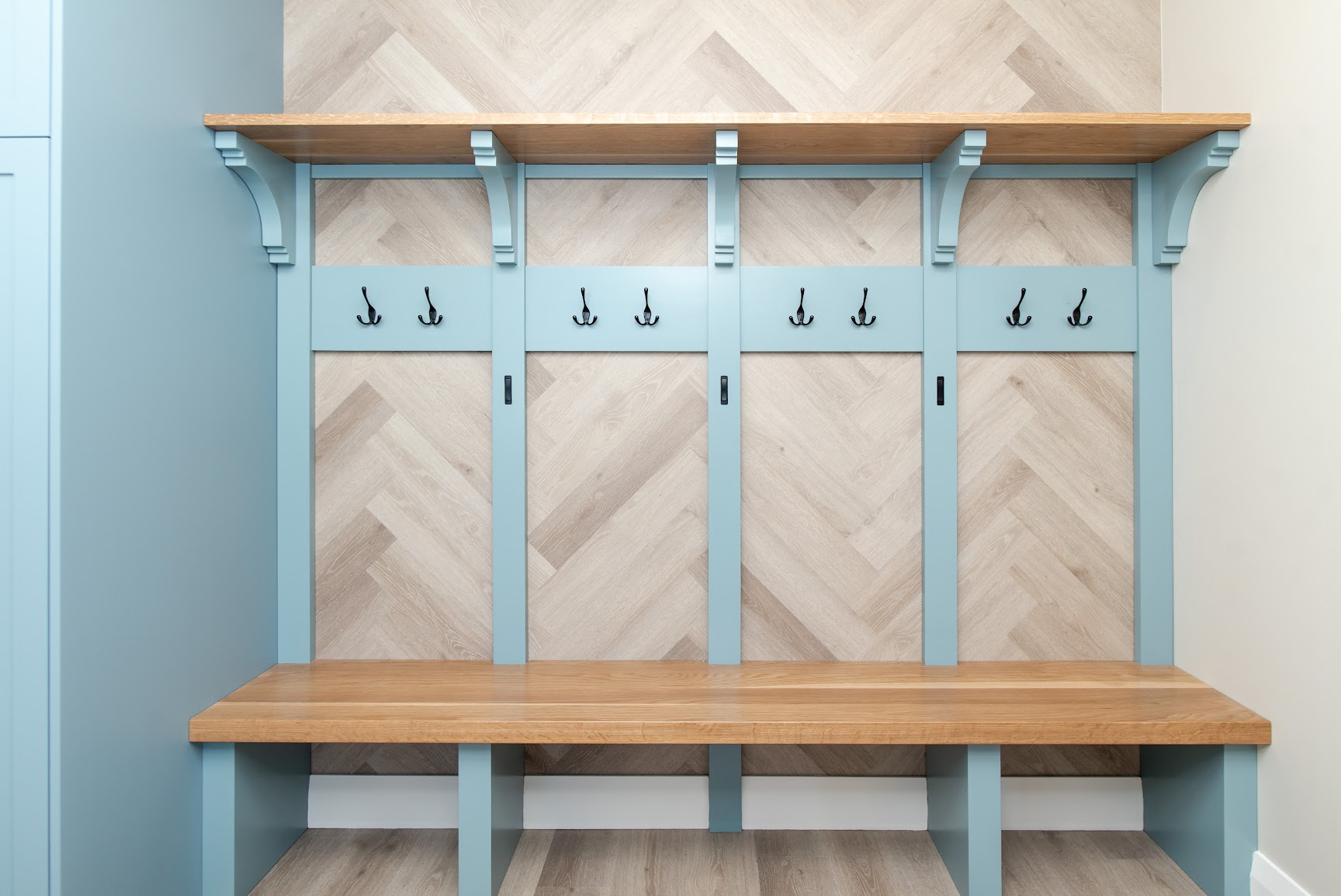 Custom mudroom bench with coat hooks and herringbone panelling, built for ski country living by Revel Homes, Blue Mountains