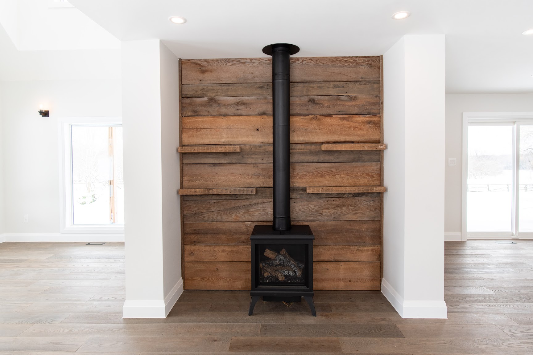 Wood stove and reclaimed barn board feature wall in a Mulmur custom home by Revel Homes