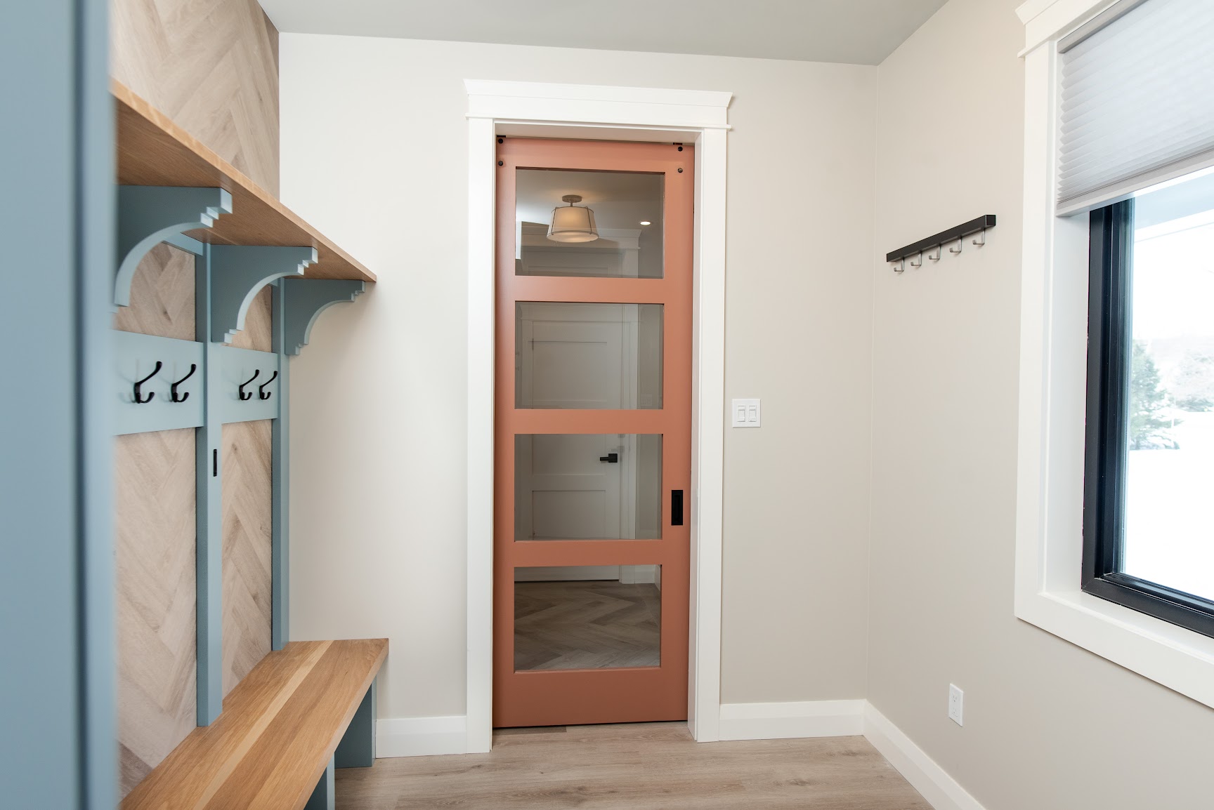 Custom mudroom with built-in bench, coat hooks and sliding glass door in a Collingwood home renovation by Revel Homes