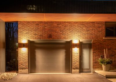 Brick garage and driveway of a custom home at dusk by Revel Homes