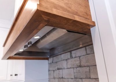 Custom wood range hood over stone in a Revel Homes kitchen