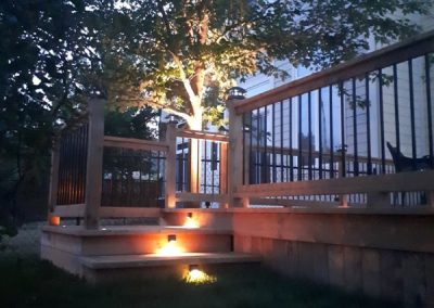 Custom deck with lighting at evening by Revel Homes