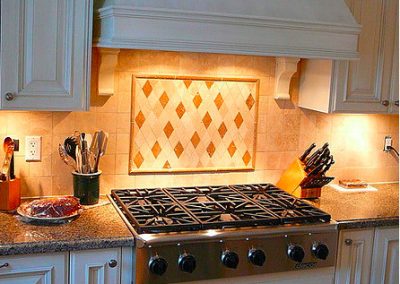 Ornate kitchen range hood and custom cabinetry by Revel Homes