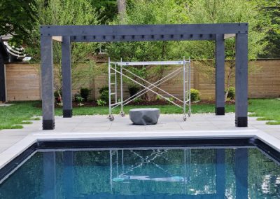 Black pergola over a pool deck built by Revel Homes